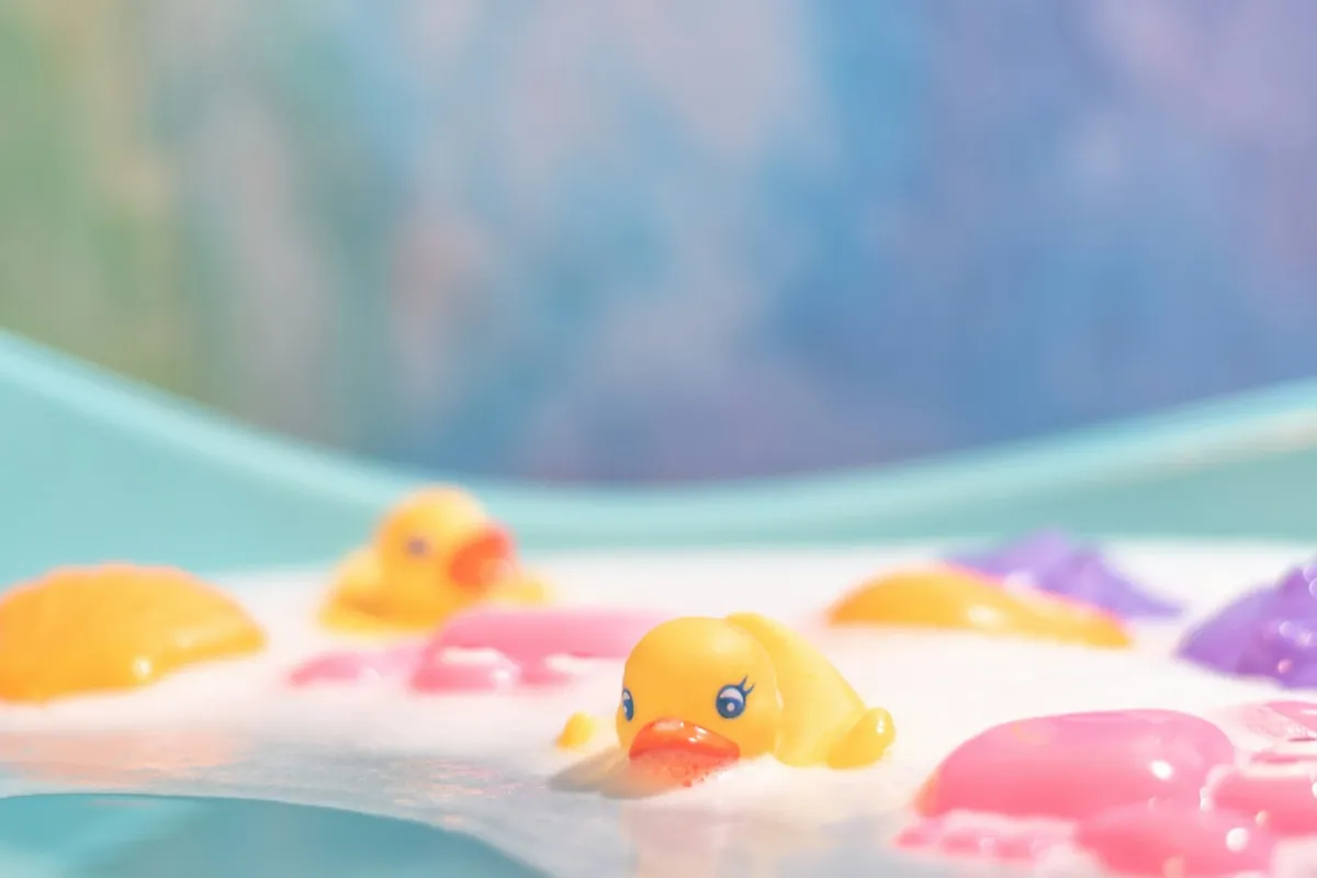 Colourful rubber ducks floating in a bath filled with bubbles and foam