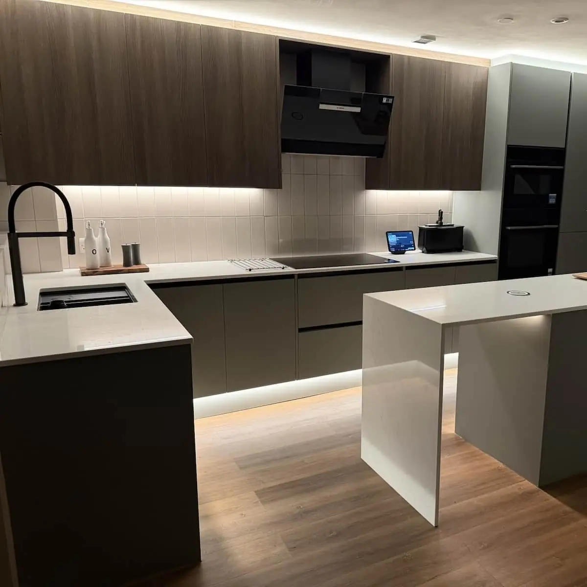 Kitchen with dark timber-effect wall units, matt handleless base units, waterfall island, and LED lighting