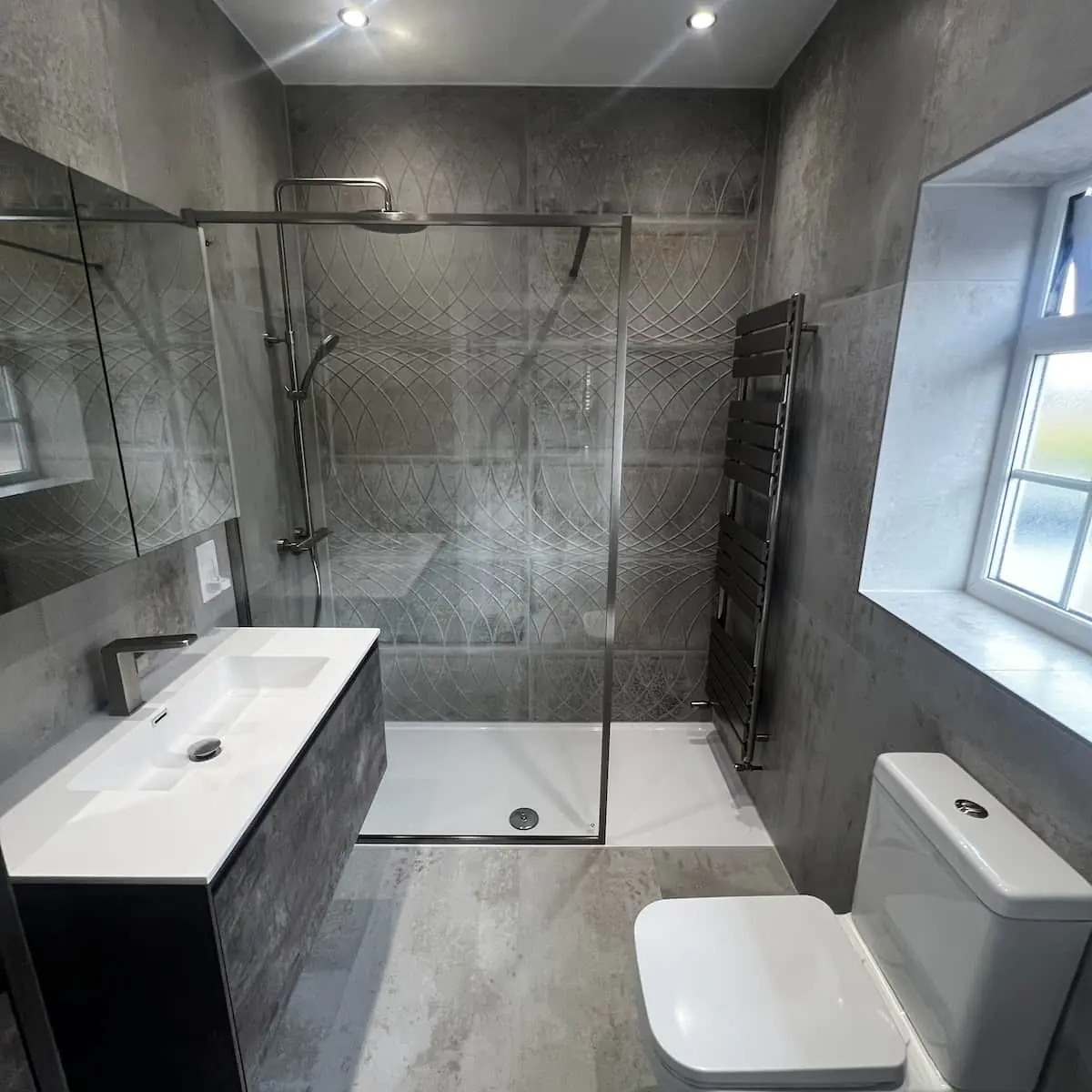 Altrincham bathroom with concrete-effect tiles, embossed patterned shower wall, and wall-hung vanity