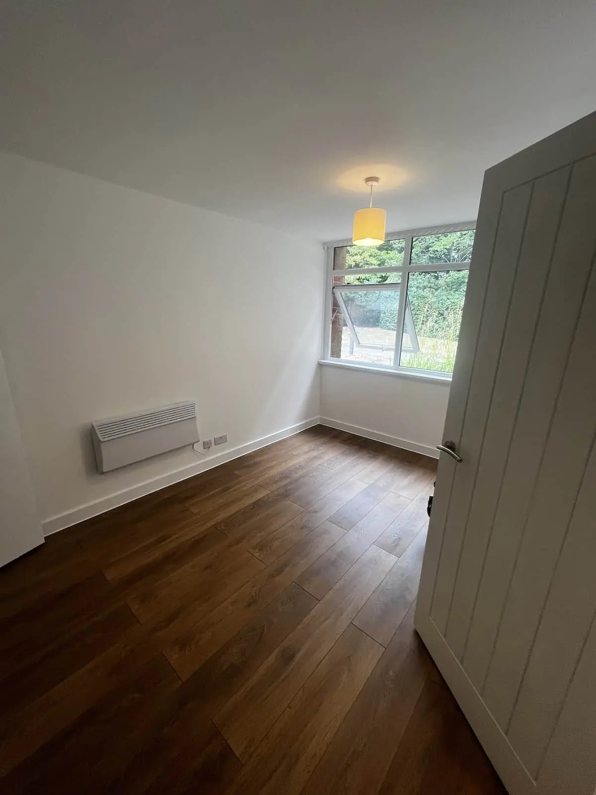 Finished room in a one-bedroom flat in Sale with fresh plaster, white woodwork, and wood-effect flooring