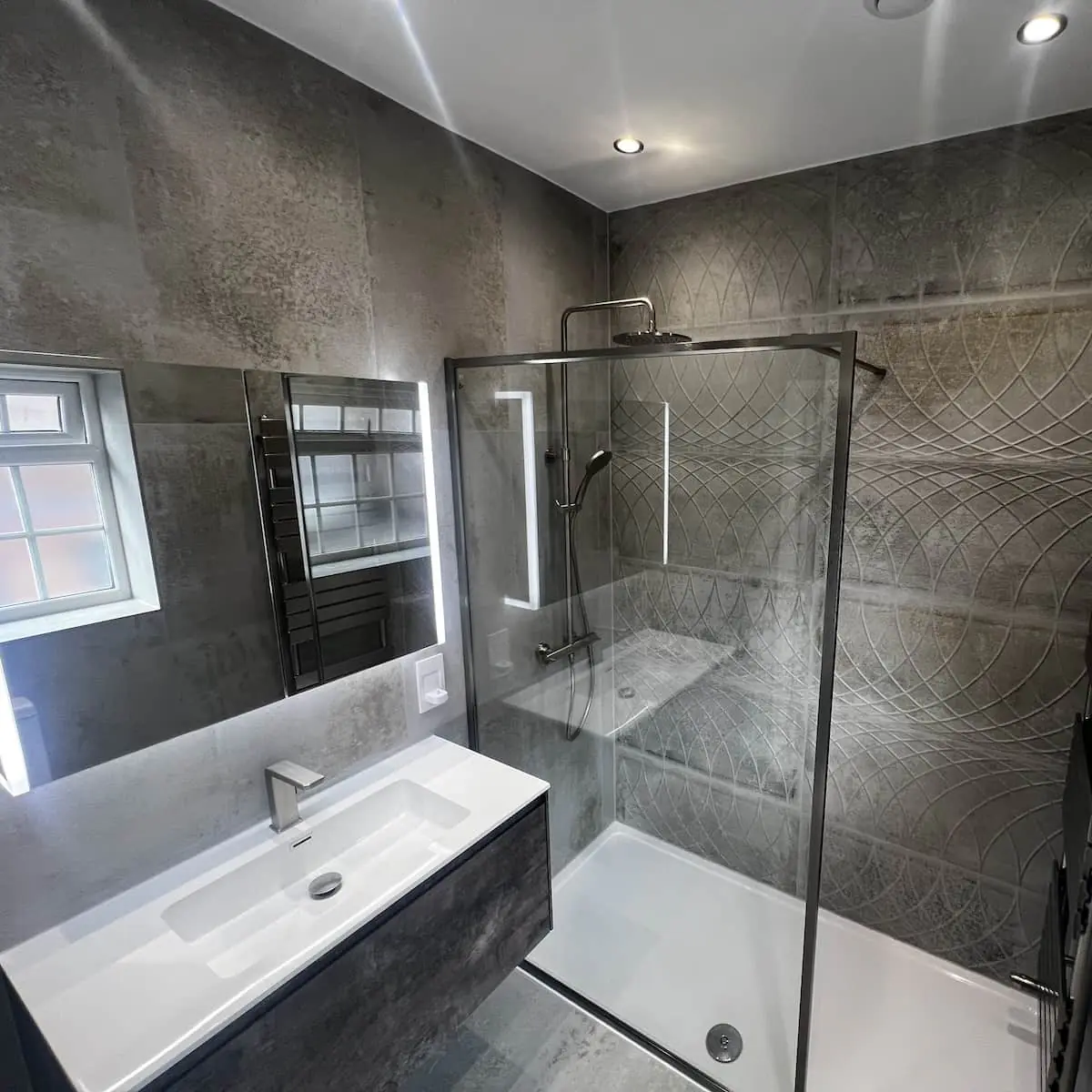 Altrincham walk-in shower with brushed metal fittings, LED mirror cabinet, and concrete-effect tiles