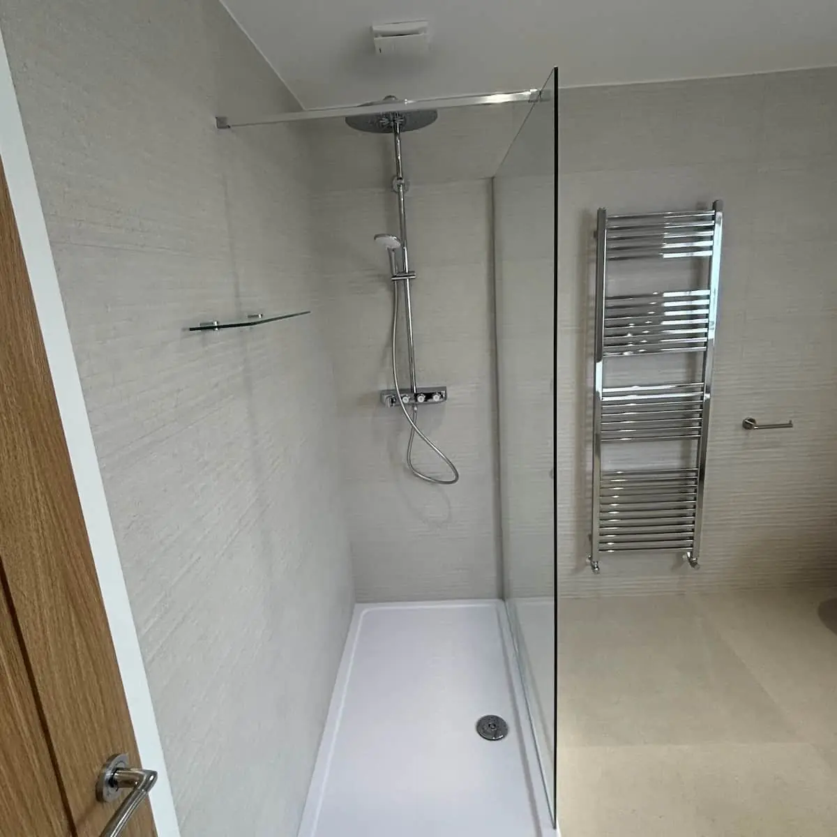 Walk-in shower with fixed glass screen, rainfall head, and bar mixer in a Poynton bathroom